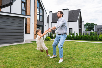 Playful mood. Happy sweet girl holding his fathers hands while playing with him