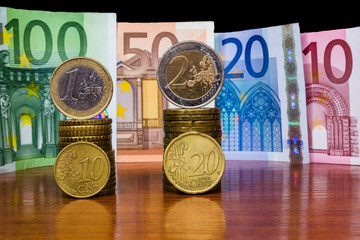 Close Up Highlighted Euro Money Banknotes And Coins Stacked On Each Other With Reflection On The Table In Vertical Position. ?ash Background. Money Bills. Finance And Economy Concept. Selective focus.