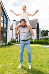 Childish fears. Nice pleasant girl sitting on her fathers shoulders while being afraid of height