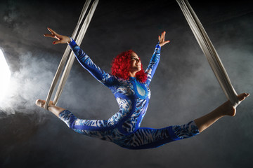 athletic sexy aerial circus artist with redhead in blue costume dancing in the air with balance