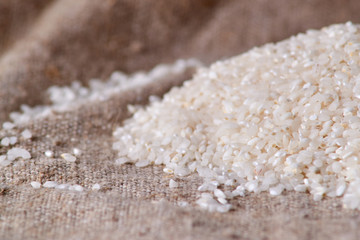 Raw rice is scattered on sackcloth. Uncooked food. selective focus