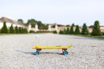 Obraz premium Gesundes Getränk auf gelben Skateboard im Park. Healthy drink standing on a yellow skateboard in a park.