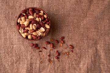 Deep fried peanuts in clay bowl over rustic wicker background. Selective focus
