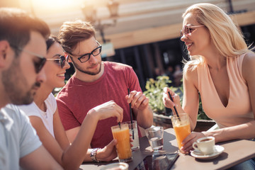 Happy young friends meeting and drinking coffee at cafe