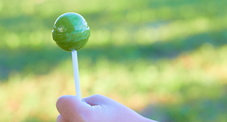 Round lollipop on a stick in hand.