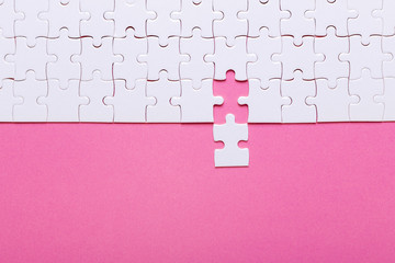White puzzle on pink background. Top view