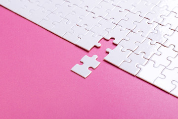 White puzzle on pink background. Top view
