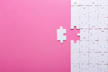 White puzzle on pink background. Top view