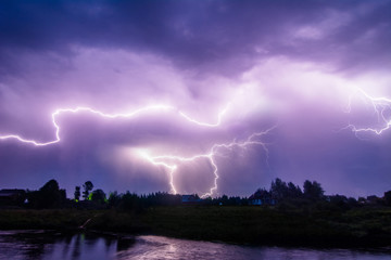 Naklejka na ściany i meble Composition photo of different lightning bolts. Thunderstorm with dramatic clouds. Lots of lightnings over the night village near river bank. Bad weather concept.