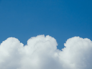 Obraz premium White curly clouds against the blue sky.