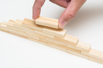 Hand adding final piece to block tower. Business solutions and problem solving concept