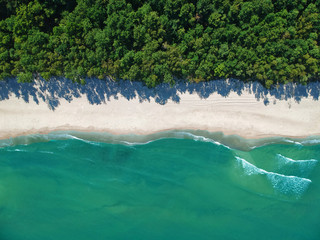 Aerial view on turquoise ocean water with clean sand beach and forest