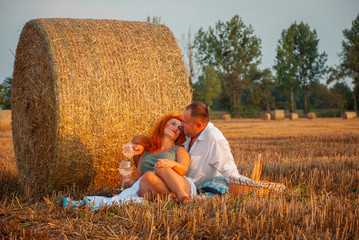 Naklejka na ściany i meble Romantic rendezvous on a freshly cut field near a haystack