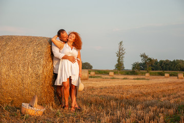 Romantic rendezvous on a freshly cut field near a haystack