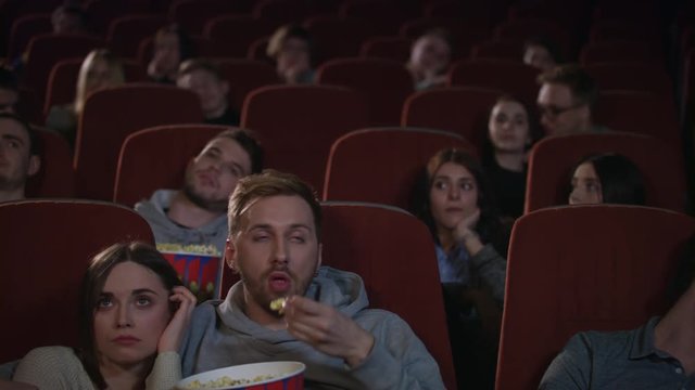 Bored people watching film in cinema. Bored audience leaving cinema while session in slow motion. Guy sleep during movie show. Uninteresting film concept