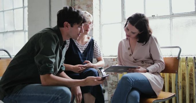 Young adults in a meeting in a creative studio with a digital tablet