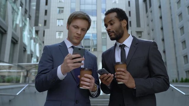 Colleagues at coffee break showing photos from vacation on phone, communication