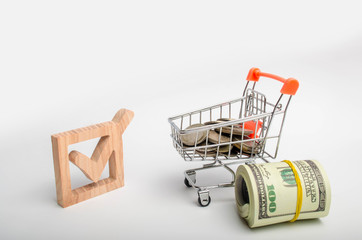 Wooden checkbox and a cart with money. Attracting resources and resources to solve problems....