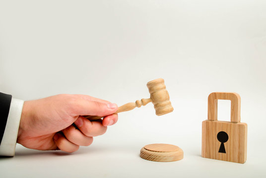 A judge's hand with a hammer near a wooden lock. Cancellation of bank secrecy. Protection of rights and freedoms of the population. Protection of personal data of users on the Internet.
