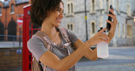 Gorgeous African female takes selfie near vintage telephone booth in London