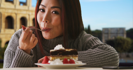 Happy Japanese woman enjoys slice of cake near Colosseum