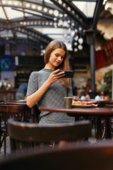 Woman In Cafe Taking Food Photo On Mobile Phone