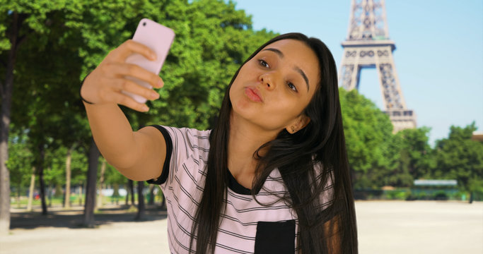 Latina female near Eiffel Tower taking selfies to post on social media