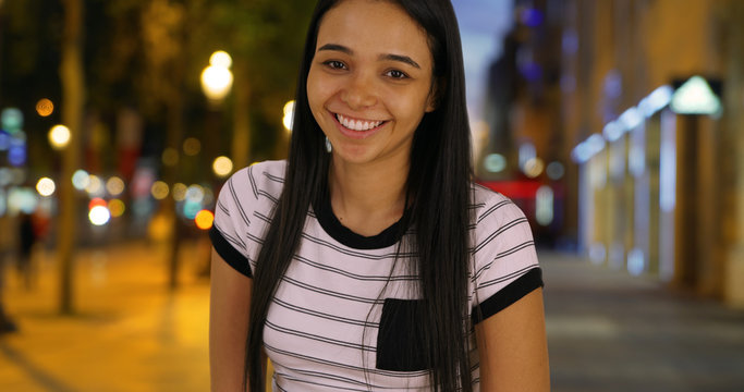 Portrait of happy attractive Latin female on Champs Elysees avenue at night