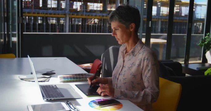 Female graphic designer using graphics tablet at desk 4k