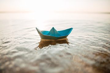 Paper boat on a blue sea background. Summer by the sea
