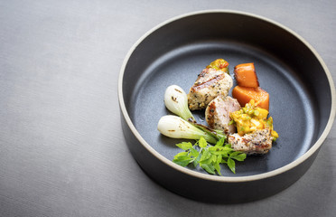 Modern barbecue crocodile tail eye fillet with roasted sweet potatoes and mango chili chutney as top view on a plate with copy space left .