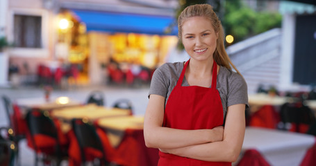 Pretty Caucasian caterer posing and standing outside restaurant in Italy