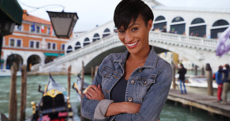 Hip happy black female standing with arms crossed near Rialto Bridge in Venice