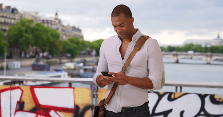 Modern Black man traveling in Paris France using smartphone outside