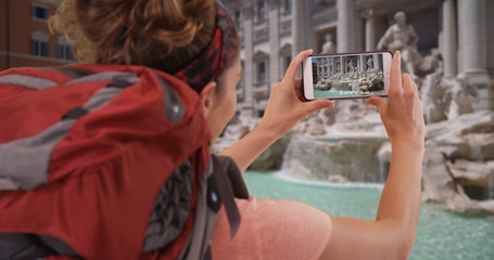 White brunette traveling in Rome recording video of Trevi Fountain on phone