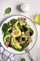 Avocado spinach salad with tuna, boiled eggs and olive oil.Top view.