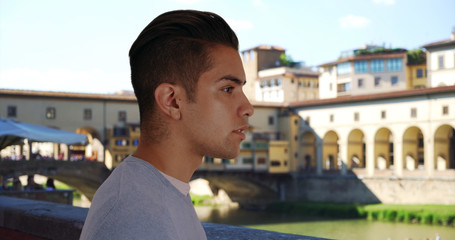 Side view of attractive Latin male standing near Ponte Vecchio bridge