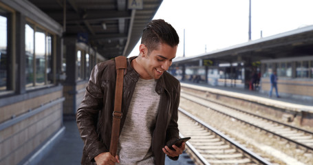 Handsome millennial Latin male at the train station hailing a ride