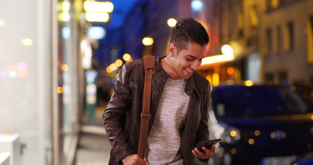 Latin millennial guy on city street at night hailing a cab or rideshare car - obrazy, fototapety, plakaty