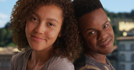 Smiling African American couple sit back to back outside in Florence