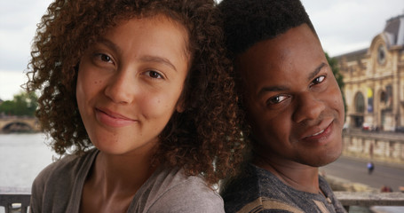 Casual portrait of African American couple sitting back to back by the Seine