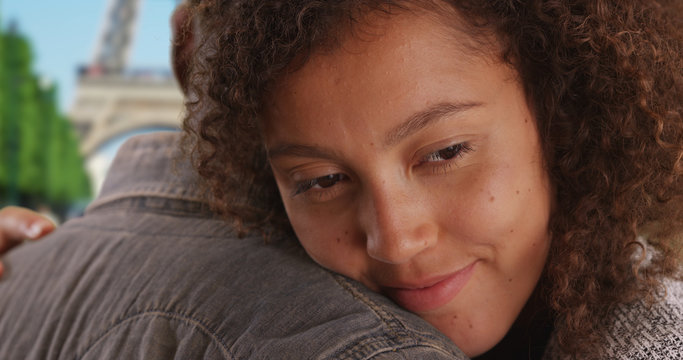 African American female is held by her sweet boyfriend near the Eiffel Tower
