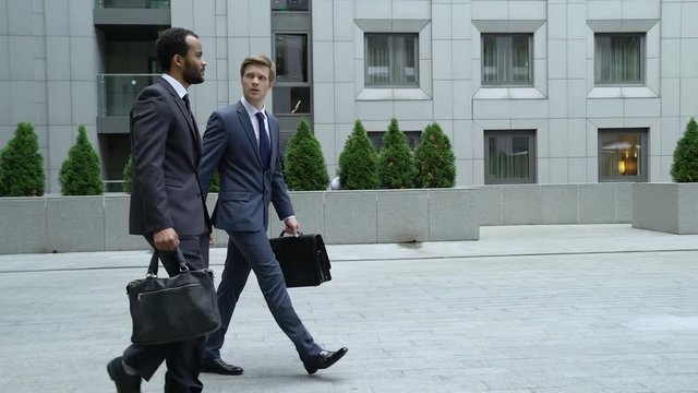 Businessmen talking outdoors, new employee trying to make friends with coworker