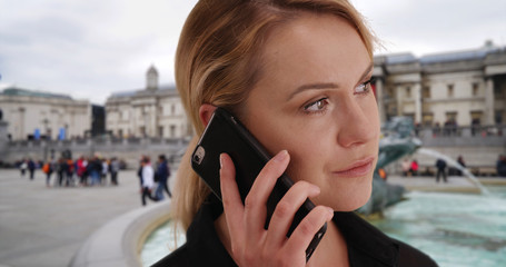 Close-up of pretty white female in London talking on phone at Trafalgar Square