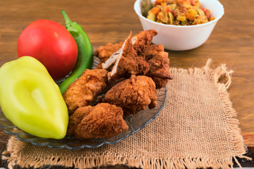 Fried in oil battered fish, stacked on a plate with pepper, tomato.