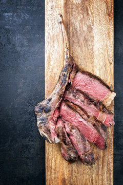 Barbecue dry aged wagyu tomahawk steak sliced as top view on a wooden board with copy space