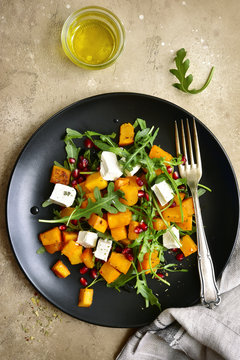 Delicious autumn pumpkin salad with arugula, feta cheese and pomegranate seeds.Top view.