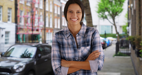 Portrait of happy and attractive woman in her 20s standing on street smiling at camera