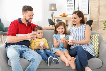 Happy family with glasses of milk in living room
