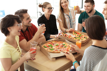Young people having fun party with delicious pizza indoors